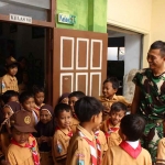 Salah satu anggota Satgas TMMD Kodim 0809/Kediri bersama Siswa MI di Desa Gadungan. (Ist)