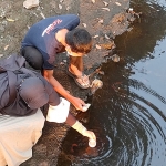 Endang Pertiwi dibantu timnya saat mengambil sampel air Sungai Kresek untuk dibawa ke laboratorium. foto: MUJI HARJITA/ BANGSAONLINE