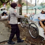 Sejumlah personel dari kepolisian sedang membagikan nasi kotak.