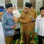 Bupati Pamekasan Baddrut Tamam saat memasangkan seragam kepada salah satu CJH. foto: ERRI/ BANGSAONLINE