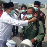 Gus Ipul memakaikan masker kepada para pengguna jalan di Manyar. foto: SYUHUD/ BANGSAONLINE