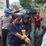 Pelaku tiba di Polres Trenggalek dengan tangan diborgol. foto: HERMAN/ BANGSAONLINE