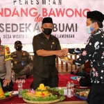 Bupati Fadeli memberikan potongan tumpeng kepada Mujiono, Kades Deketagung. (foto: ist).