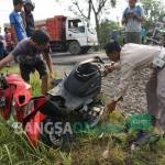 Petugas bersama warga saat hendak mengevakuasi motor korban yang ringsek usai digilas kereta api. foto: RONY S/ BANGSAONLINE