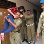 Terjaring razia, anggota Satpol PP Kota Surabaya menggendong anaknya sendiri dari kamar hotel untuk diajak pulang. foto: tribunkota.com