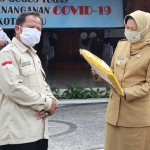 Kepala SMKN 1 Batu Joko Santoso saat menyerahkan bantuan APD dan masker kepada Wali Kota Batu Dra. Dewanti Rumpoko, di halaman pendopo rumah dinas wali kota, Senin (11/5)