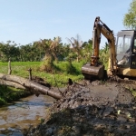 Alat berat sedang mengeruk salah satu irigasi.