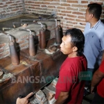 Kedua pelaku (baju merah) menunjukkan lokasi dan peralatan yang digunakan untuk menyuling arak. foto: RONY S/ BANGSAONLINE