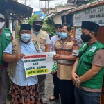 Ketua NU Care - LAZISNU Kota Surabaya, Yusub Hidayat (dua dari kanan) saat menyalurkan bantuan rombong dan modal usaha kepada Irnadi, pedagang bakso. foto: ist.