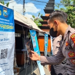 Salah satu anggota kepolisian saat memindai QR code dengan Aplikasi PeduliLindungi. foto: ist.