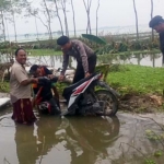 Salah satu pengendara yang nekat melintasi tercebur di kubangan jalan yang putus setelah digerus air banjir. foto: EKY NURHADI/ BANGSAONLINE