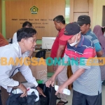 Petugas dari Kemenag Situbondo saat menyerahkan koper kepada CJH.