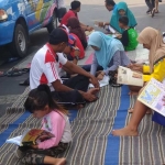 Warga yang berkunjung di Alun-alun Lamongan tangah membaca buku yang disediakan mobil Pustaka Keliling.