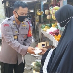 Kapolsek Prambon AKP Hery Moeryanto Tampake saat ikut membagikan masker. (foto: ist)