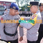 Kapolres Gresik, AKBP Adhitya Panji Anom, ketika memasang pita kepada anggota yang bertugas menjadi Polisi RW. Foto: SYUHUD/BANGSAONLINE