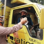 Kapolsek Manyar AKP Windu Priyo Prayitno membagikan nasi bungkus dan air mineral kepada sopir truk yang terkena kemacetan di jalur pantura. foto: SYUHUD/BANGSAONLINE