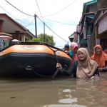 Warga saat menggunakan perahu karet untuk menerjang banjir di Kabupaten Pasuruan.