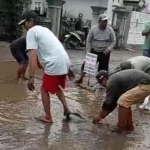 Warga Desa Ngembul Kecamatan Binangun Kabupaten Blitar saat melepaskan lele hidup di kubangan jalan. 