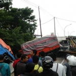 Mobil derek berupaya mengangkat truk gandeng yang masuk ke dalam parit.