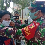 Pelda Masduki saat memakaikan masker kepada warga.