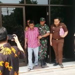 Irwan Yudhianto (baju garis-garis) ketika keluar dari kantornya di Jl. Pemuda Kaffa Ruko Graha Metro dengan dikawal anggota TNI, Kamis (17/10/2019).