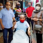 Peny Sugiharti didampingi suami saat menyalurkan bantuan kursi roda. foto: HERMAN/ BANGSAONLINE