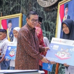Gubernur DKI Jakarta saat menyalurkan KJP Plus secara simbolis kepada salah satu penerima.