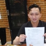 Vidi Bagus P, perwakilan dari owner Warunk Upnormal saat menunjukkan perizinan yang dimilikinya selama ini, berupa UK-UPL (izin lingkungan) dan pajak reklame, Selasa (15/01) malam. foto: IWAN IRAWAN/ BANGSAONLINE