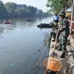 Para Prajurit Koarmada II sedang menjaring sampah di Kali Mas.