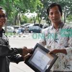 Plt  Sekkab Gresik, ketika memberikan piagam penghargaan kades peduli kesehatan. foto: syuhud/ BANGSAONLINE