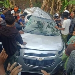 Warga berusaha mengevakuasi korban yang sempat terjebak di dalam mobil.