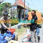 Personel Polres Gresik saat droping air bersih di Desa Tumapel, Kecamatan Duduksampeyan. Foto: SYUHUD/BANGSAONLINE