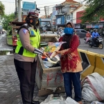 Seorang Polwan Satlantas Polres Gresik saat membagi sembako kepada pemulung. foto: ist.