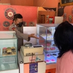 Anggota Bagops Polresta Sidoarjo, Bripka Dwi Agung Runsubekti, saat melayani pelanggan yang hendak membeli donat buatannya.