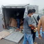 Petugas melakukan evakuasi galon mineral dengan cara dikeluarkan dari boks truk lalu dipindahkan ke truk boks yang lain.