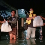 Pengurus DPD Golkar Pasuruan dibantu kader AMPG saat membagikan nasi bungkus ke korban banjir.