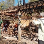 Saeran (kanan) sedang mengangkat sejumlah besi beton.