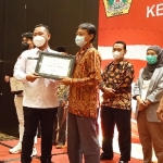 Bupati Gus Yani menyerahkan penghargaan kepada Ahmad Wahib, perwakilan PT Wilmar Nabati Indonesia sebagai mitra UMKM. foto: SYUHUD/BANGSAONLINE.com