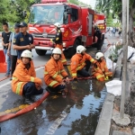 Para petugas PMK sedang menyemprotkan air ke selokan. foto: ist.