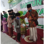 Tampak Ketua PCNU Bangil H. M. Shobri saat membagikan uang kepada anak yatim.