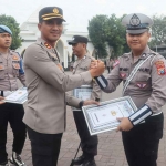 Kapolres Pasuruan, AKBP Bayu Pratama Gubunagi, saat memberi penghargaan kepada salah satu personel berprestasi.