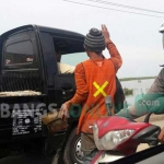 Salah satu polisi cepek membawa ember sembari meminta uang kepada kendaraan besar yang hendak melintas di jalan Betoyo-Pecuk. foto: SYUHUD/ BANGSAONLINE