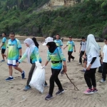 Sekelompok orang yang tergabung dalam komunitas sosial sedang melakukan aksi bersih-bersih pantai.