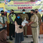 Darmono, Kades Wanglu Kulon saat menyerahkan bantuan sembako secara simbolis kepada salah satu warga.