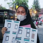 Risky Purnaningsari sedang menunjukkan bukti-bukti membernya melarikan uang miliknya, usai melapor ke Polres Kediri Kota. foto: MUJI HARJITA/BANGSAONLINE