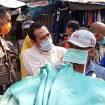 Wabup Moh. Qosim saat memasang masker kepada pedagang es dawet di Pasar Gresik, Rabu (25/3). foto: SYUHUD/ BANGSAONLINE