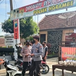 Personel Polsek Ngrambe Ngawi saat berbagi nasi bungkus dan masker pada masyarakat yang melintas.