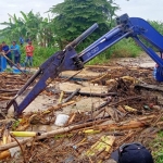 Petugas dengan alat ekskavator saat membersihkan rumpon bambu yang menyumbat Anak Sungai Kali Lamong. (foto: ist)