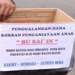 Warga menggunakan kotak kardus saat menggalang dana untuk Sai