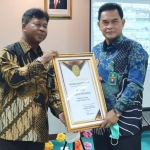 Direktur Jenderal Badan Peradilan Umum Mahkamah Agung RI, Dr. H. Prim Haryadi, S.H., M.H., (kiri) saat menyerahkan sertifikat piagam penghargaan kepada Ketua Pengadilan Tinggi Surabaya, Dr. H. Herri Swantoro, S.H., M.H., (kanan). (foto: ist).